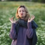 Young woman playfully pouts in a lush, blooming meadow during spring.
